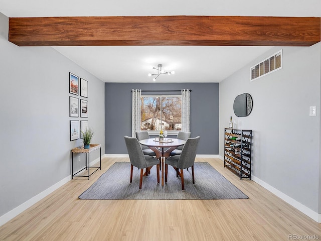 dining space featuring beam ceiling and light wood-type flooring