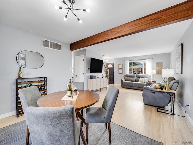 dining space with beam ceiling, a chandelier, and light wood-type flooring