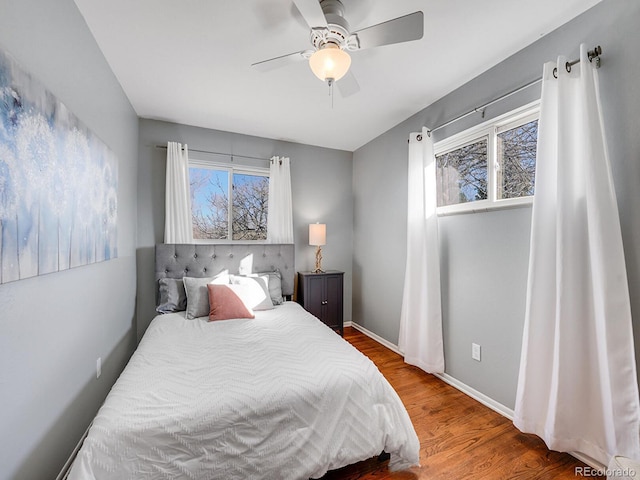 bedroom featuring multiple windows, hardwood / wood-style floors, and ceiling fan