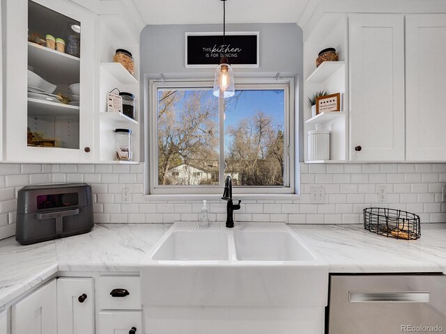 kitchen featuring sink, backsplash, white cabinets, hanging light fixtures, and light stone counters