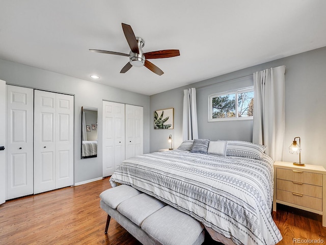 bedroom with hardwood / wood-style flooring, ceiling fan, and two closets