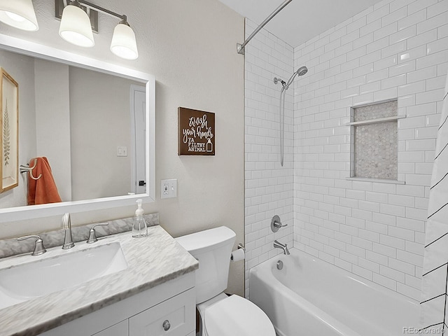 full bathroom featuring tiled shower / bath, vanity, and toilet