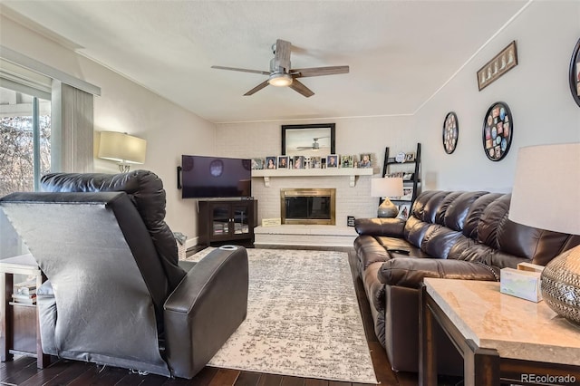 living room featuring ceiling fan, a brick fireplace, and dark hardwood / wood-style flooring