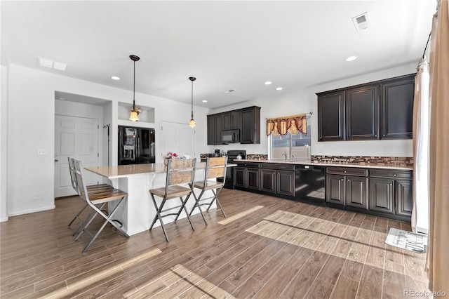 kitchen featuring black appliances, a kitchen breakfast bar, visible vents, and light wood-type flooring