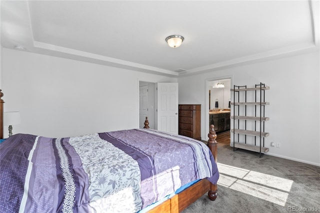 bedroom featuring a raised ceiling, ensuite bathroom, and carpet flooring