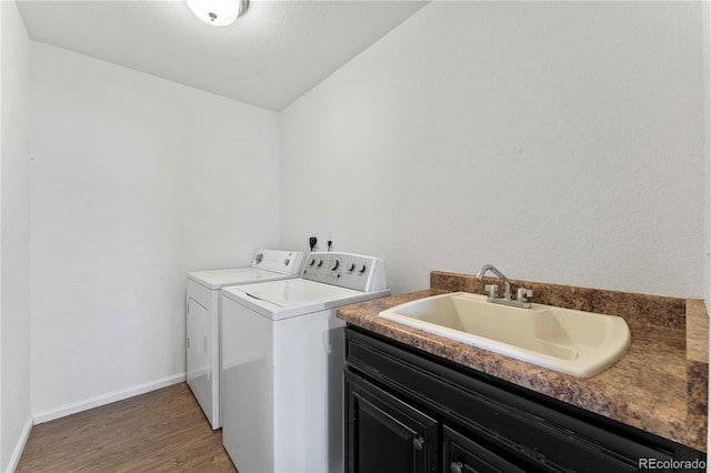 clothes washing area with baseboards, separate washer and dryer, wood finished floors, cabinet space, and a sink