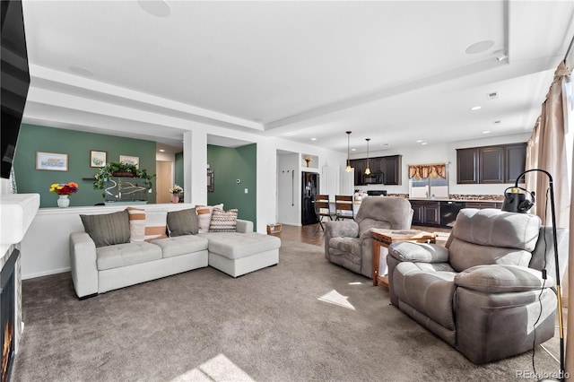 carpeted living area featuring recessed lighting and a sink