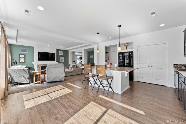 kitchen featuring black fridge, decorative light fixtures, a kitchen bar, and visible vents