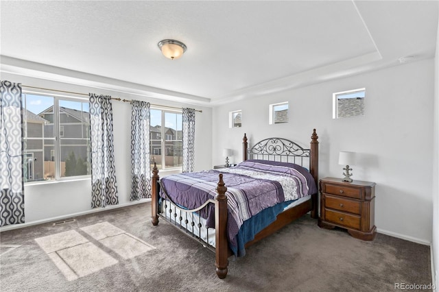 bedroom with carpet flooring, visible vents, and a tray ceiling