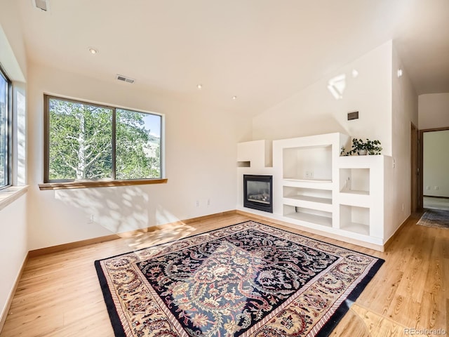 40 Cove Blvd Unit G40, Dillon, CO 80435 - unfurnished living room with wood finished floors, built in features, a glass covered fireplace, baseboards, and lofted ceiling