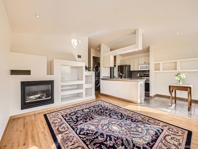 40 Cove Blvd Unit G40, Dillon, CO 80435 - living room featuring stacked washer and clothes dryer, a glass covered fireplace, baseboards, and light wood-style flooring