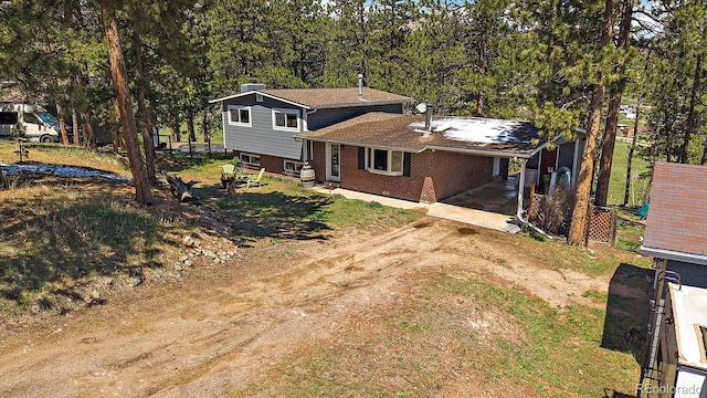 29827 Gigi Rd, Evergreen, CO 80439 - rear view of house featuring dirt driveway, brick siding, and a carport