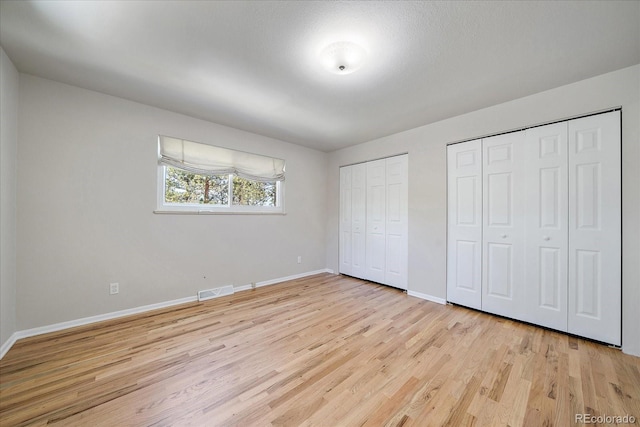 29827 Gigi Rd, Evergreen, CO 80439 - unfurnished bedroom featuring multiple closets, light wood-style flooring, and baseboards