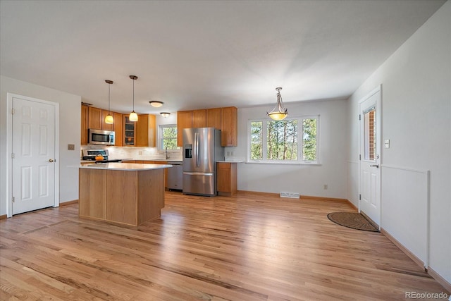 29827 Gigi Rd, Evergreen, CO 80439 - kitchen with stainless steel appliances, light wood finished floors, a kitchen island, light countertops, and brown cabinetry