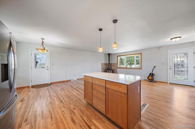 29827 Gigi Rd, Evergreen, CO 80439 - kitchen featuring stainless steel fridge, a wood stove, light wood-style floors, and light countertops