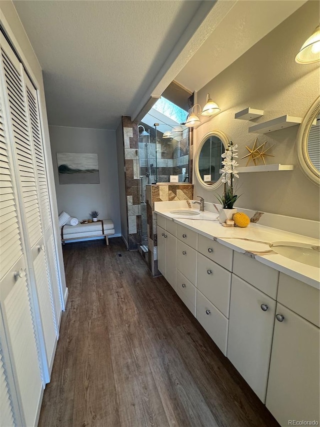 bathroom with hardwood / wood-style flooring, vanity, a shower with door, and a textured ceiling