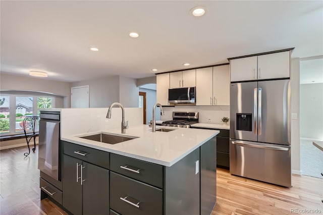 kitchen featuring appliances with stainless steel finishes, sink, a center island with sink, and gray cabinetry