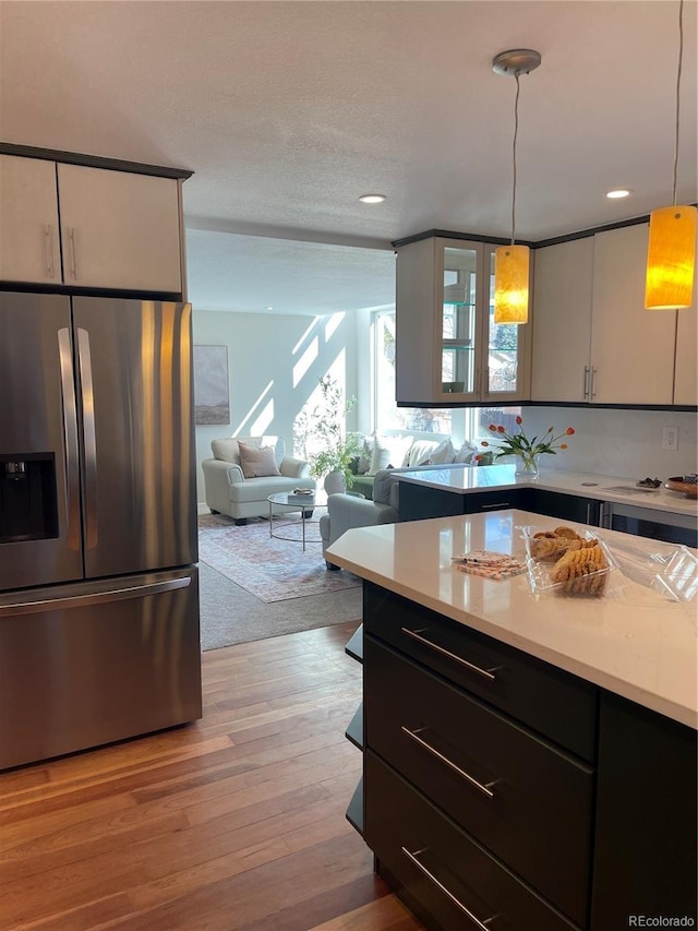 kitchen featuring hanging light fixtures, white cabinetry, and stainless steel fridge