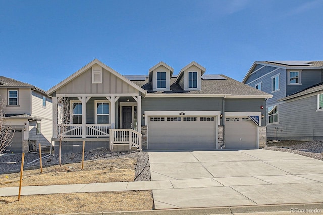 631 Sunrise St, Erie, CO 80516 - craftsman house with an attached garage, a porch, driveway, roof mounted solar panels, and stone siding