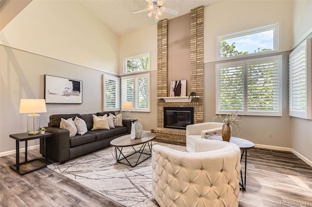 16257 E Belleview Pl, Centennial, CO 80015 - living area with high vaulted ceiling, wood finished floors, ceiling fan, a brick fireplace, and baseboards