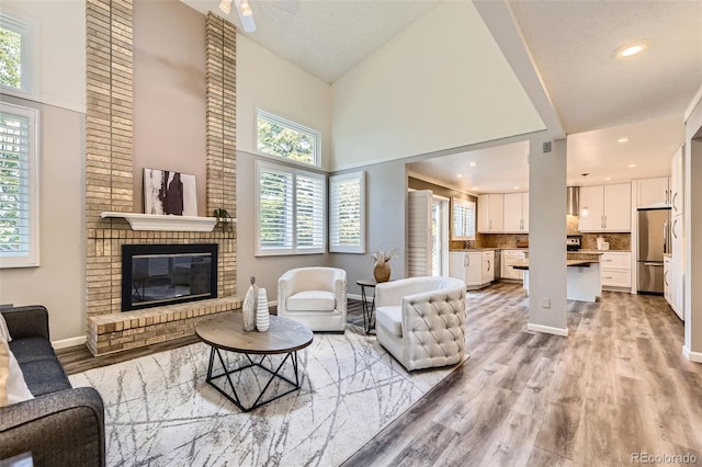 16257 E Belleview Pl, Centennial, CO 80015 - living area featuring plenty of natural light, light wood-style floors, a ceiling fan, a high ceiling, and recessed lighting