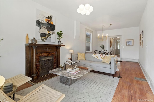 living room featuring a brick fireplace, light hardwood / wood-style floors, and a chandelier