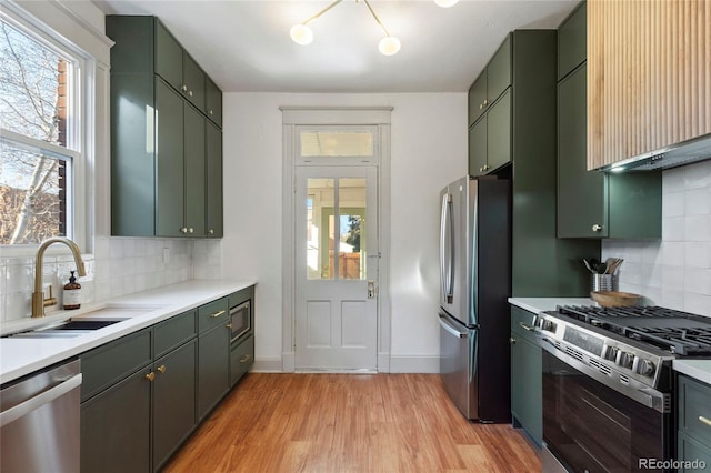 kitchen featuring appliances with stainless steel finishes, tasteful backsplash, sink, and green cabinets