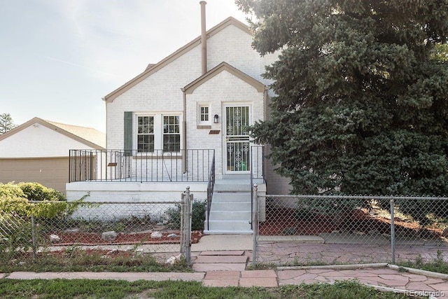 bungalow-style home with covered porch, brick siding, a garage, and a fenced front yard