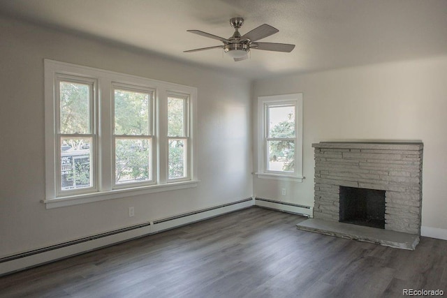 unfurnished living room with ceiling fan, a baseboard heating unit, a stone fireplace, and wood finished floors