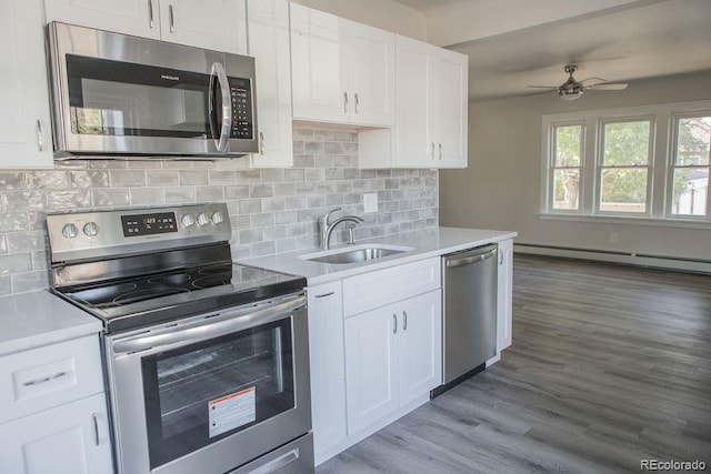 kitchen featuring a ceiling fan, a baseboard radiator, a sink, stainless steel appliances, and light countertops