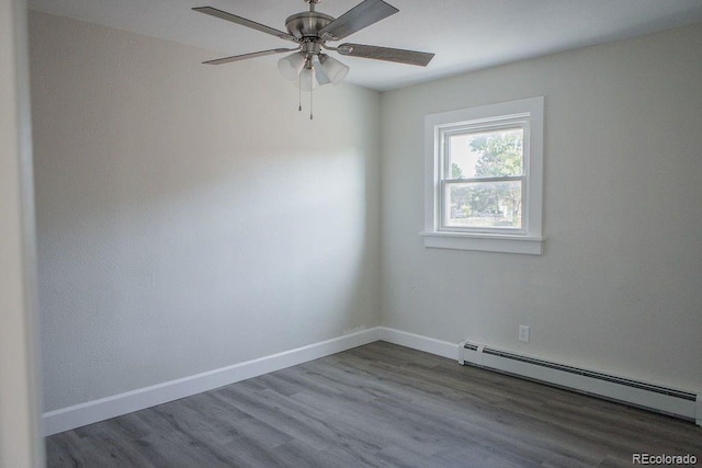 spare room featuring a baseboard heating unit, baseboards, wood finished floors, and a ceiling fan