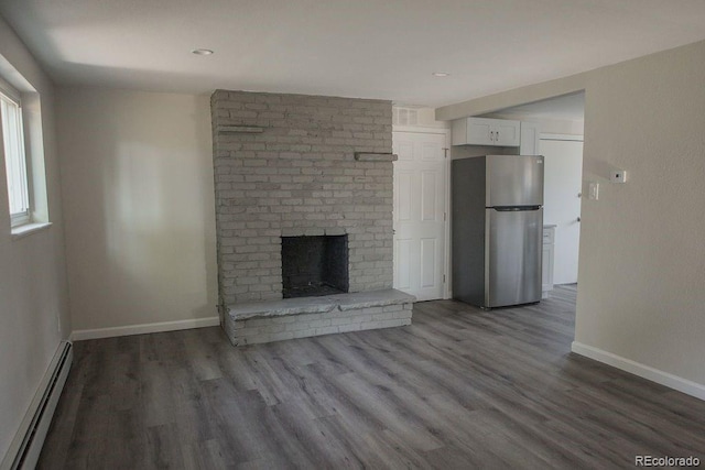 unfurnished living room featuring a baseboard heating unit, a brick fireplace, wood finished floors, and baseboards