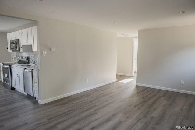 interior space featuring tasteful backsplash, stainless steel appliances, dark wood-type flooring, and baseboards