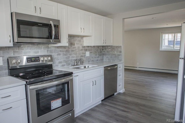 kitchen with a sink, light countertops, a baseboard heating unit, and stainless steel appliances