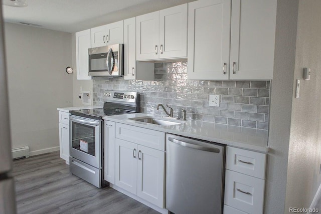 kitchen with a sink, white cabinetry, stainless steel appliances, light countertops, and decorative backsplash