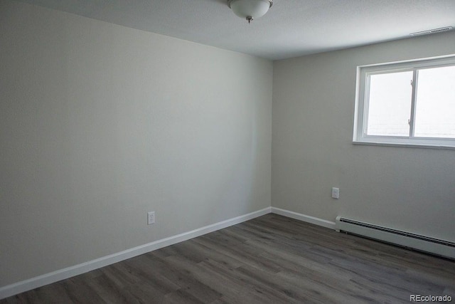 empty room with baseboard heating, baseboards, and wood finished floors