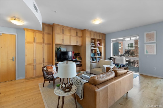 living area with baseboards, light wood finished floors, and visible vents