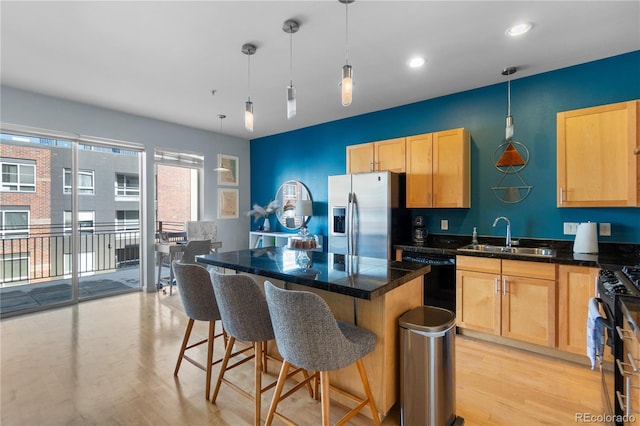 kitchen with light brown cabinetry, a kitchen island, light wood-style floors, a sink, and black appliances