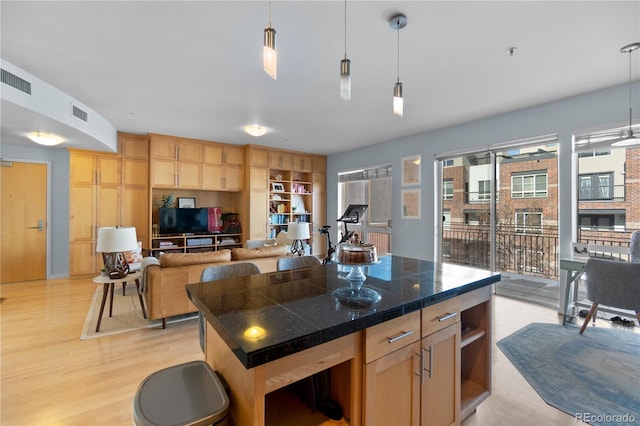 kitchen featuring light brown cabinets, tile countertops, open floor plan, visible vents, and pendant lighting