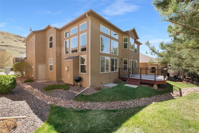 7436 Centennial Glen Dr, Colorado Springs, CO 80919 - rear view of house with stucco siding, a wooden deck, and a lawn