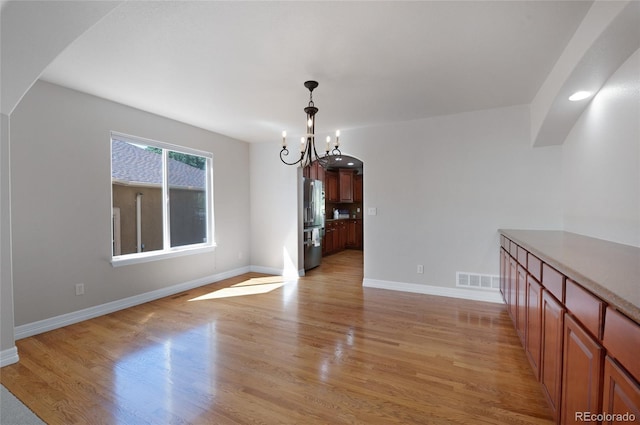 7436 Centennial Glen Dr, Colorado Springs, CO 80919 - unfurnished dining area featuring arched walkways, a chandelier, light wood-style floors, and baseboards