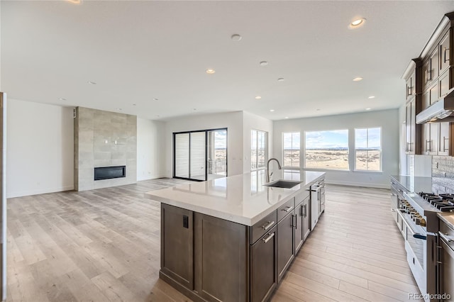 kitchen with high end stainless steel range, a center island with sink, a healthy amount of sunlight, and sink