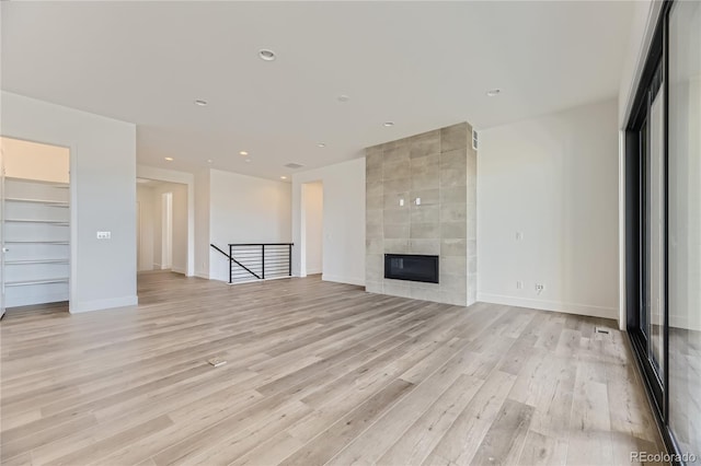 unfurnished living room featuring light hardwood / wood-style flooring and a tile fireplace