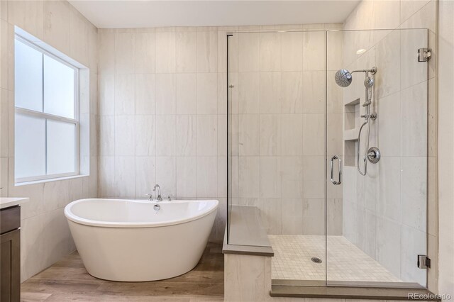 bathroom with hardwood / wood-style flooring, vanity, plus walk in shower, and tile walls