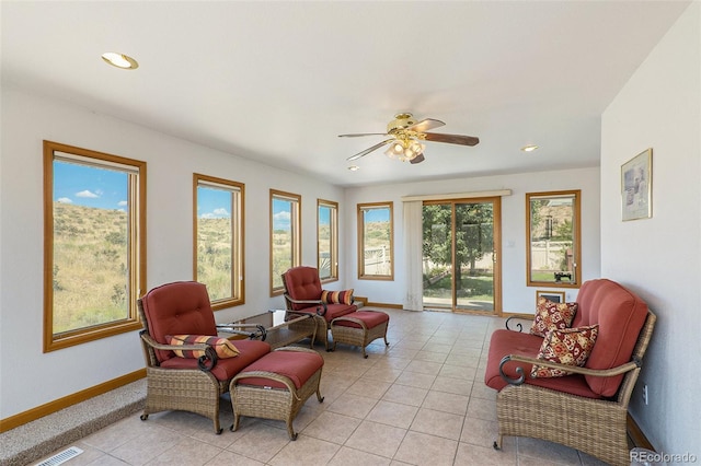 living area with a wealth of natural light, ceiling fan, and light tile patterned floors