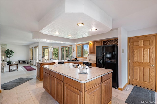 kitchen with kitchen peninsula, sink, black appliances, light tile patterned floors, and a center island