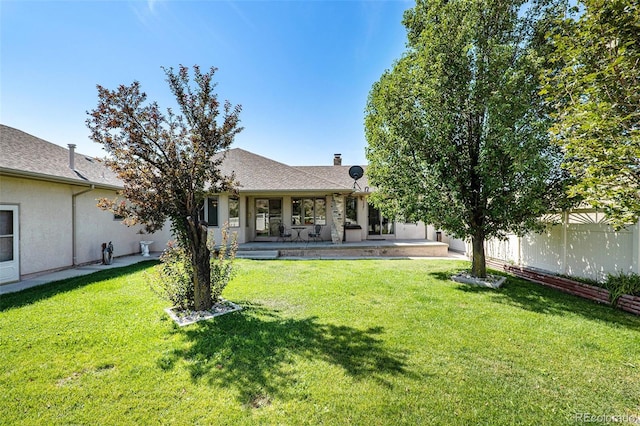 rear view of house with a lawn and a patio area