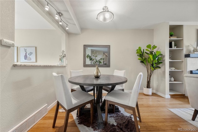 dining area featuring baseboards, baseboard heating, track lighting, and light wood-style floors