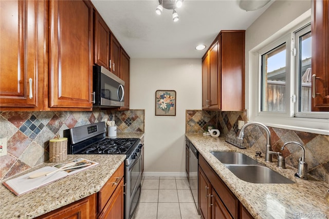 kitchen featuring light stone countertops, baseboards, a sink, decorative backsplash, and appliances with stainless steel finishes