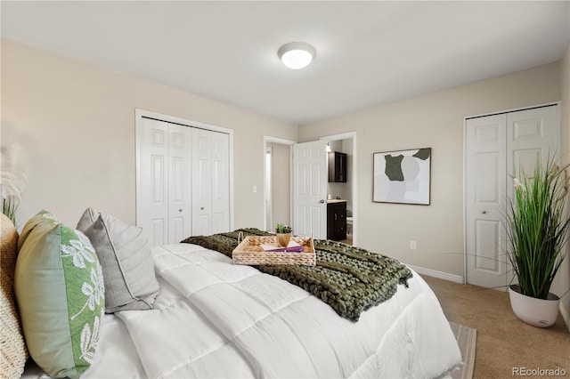 carpeted bedroom featuring a closet, ensuite bath, and baseboards